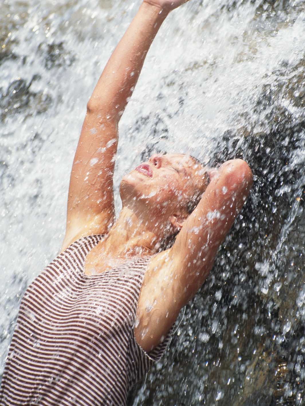 Woman beneath a natural New Zealand waterfall